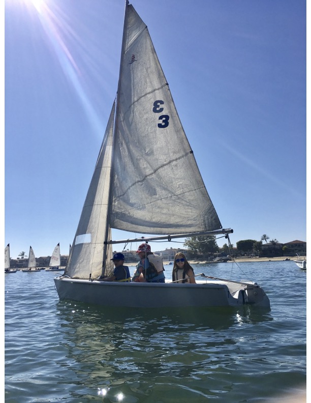 Three Children on a Sailboat in the Harbor