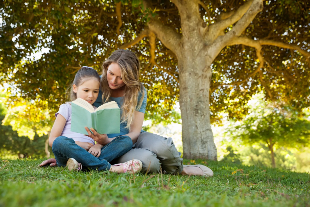 Mother Reading a Picture Book Under a Shade Tree