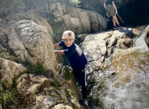 Boy Climbing on a Rocks Next to a Water Stream