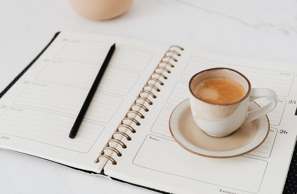 Open Planner with a Cup of Latte Sitting on Top of the Planner with a Pen