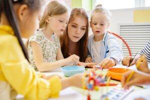 Mother Sitting Next to Two Girls While They are Painting