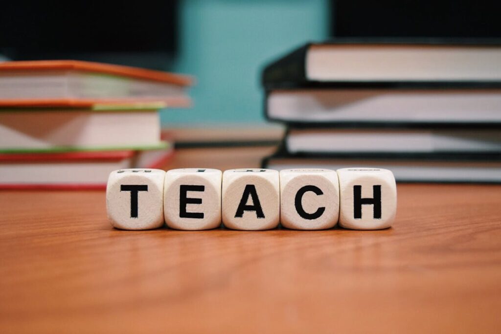 Block Letters that Spell Teach in Front of Books