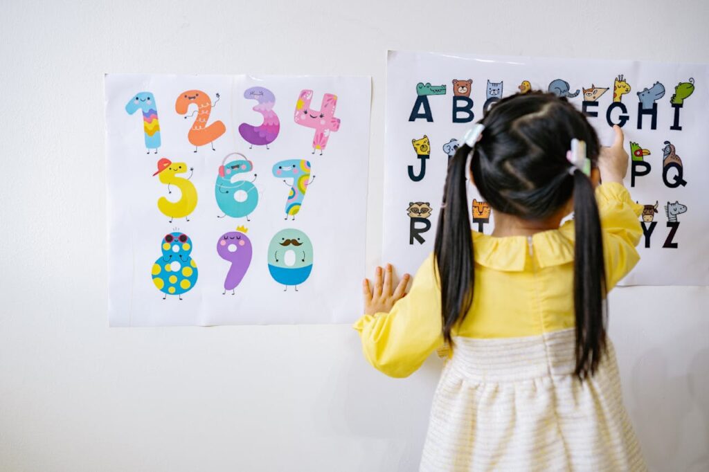 Little Girl Pointing to a Letter on an Alphabet Chart